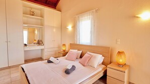 A bedroom with a bed, nightstands, a wardrobe, and a window with curtains.