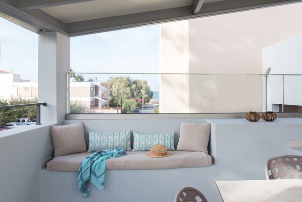 A balcony with a cushioned seating area, a woven basket, and a view of the cityscape. - A beach retreat, with 3 bedrooms, 2 full baths, up to 5 guests! (Rethymno)