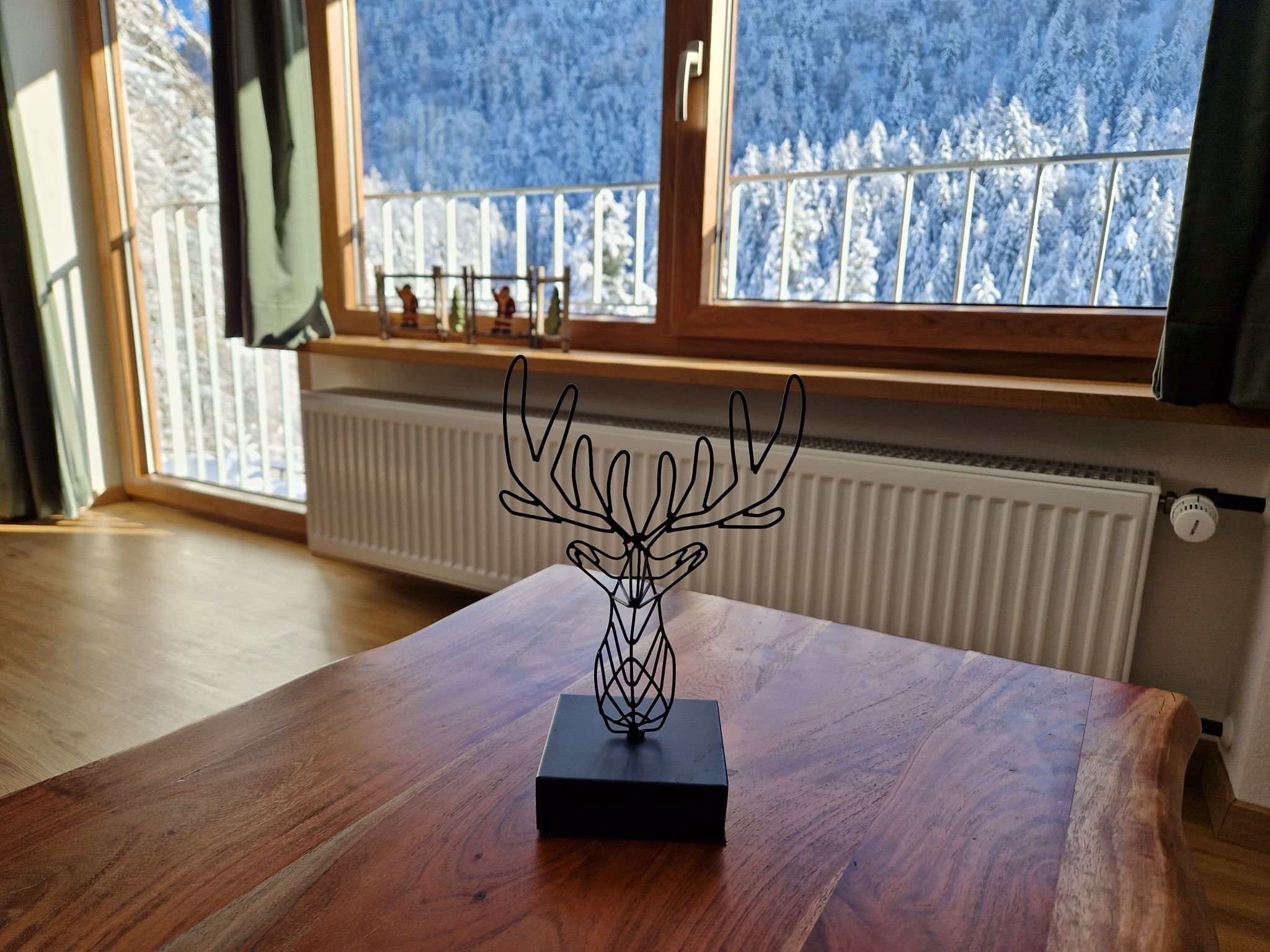 A wooden table with a black sculpture of a deer head in the center.