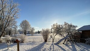 A snow-covered outdoor area with a swing set, a slide, and a fenced play area. - Großzügige Ferienwohnung zum Entspannen und Wohlfühlen, 78 m², 4 Personen, Wlan (Siegsdorf)