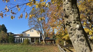 A house with a porch, surrounded by trees and a grassy yard. - Großzügige Ferienwohnung zum Entspannen und Wohlfühlen, 78 m², 4 Personen, Wlan (Siegsdorf)