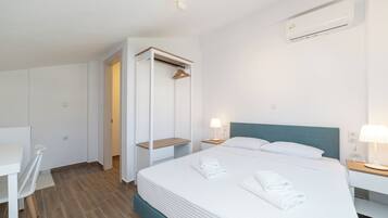 A hotel room with a bed, bedside tables, a wardrobe, and a desk.