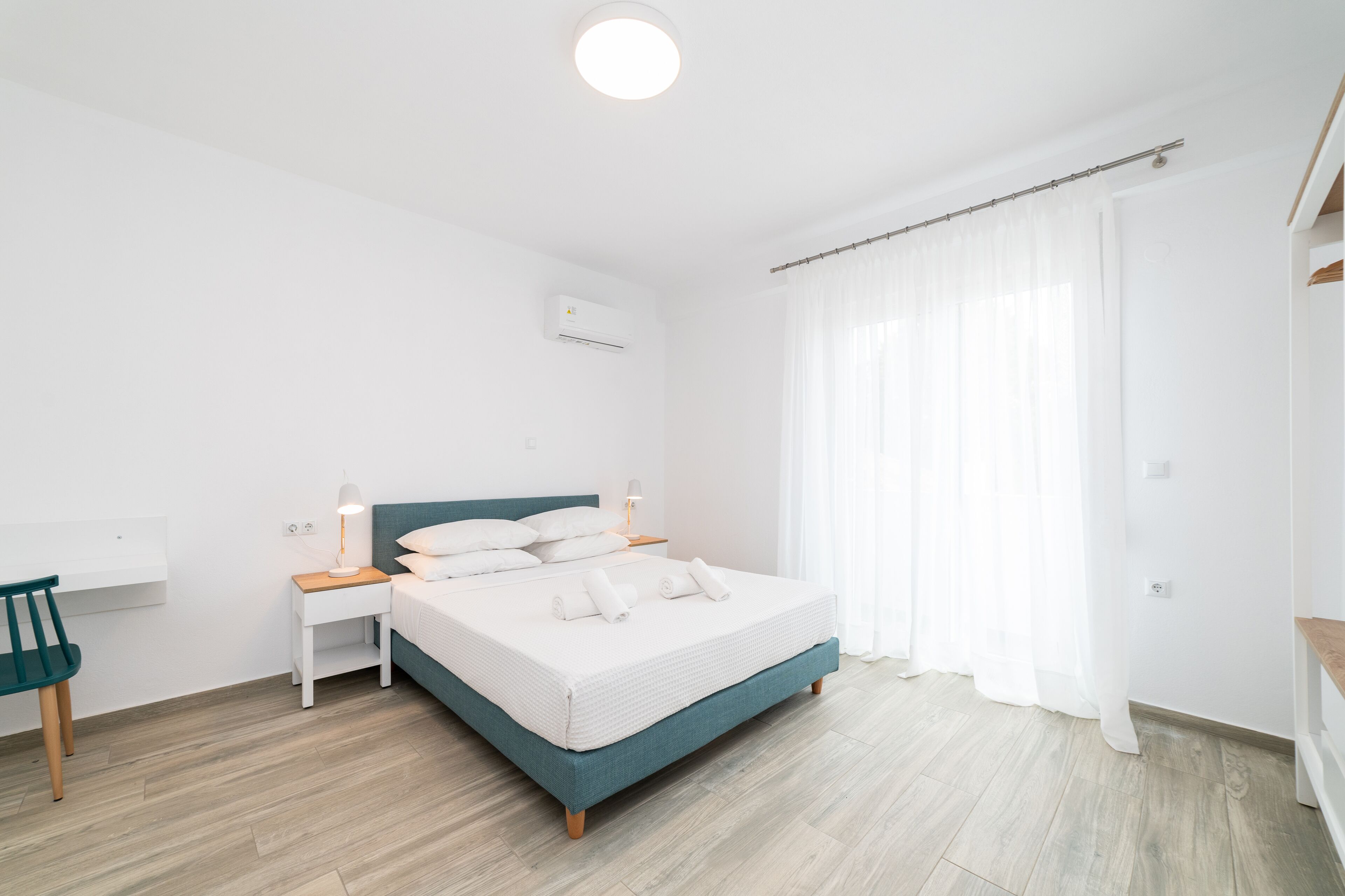 A modern bedroom with a bed, bedside tables, a desk, and a chair.