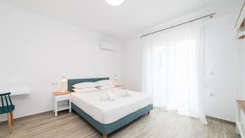 A modern bedroom with a bed, bedside tables, a desk, and a chair.