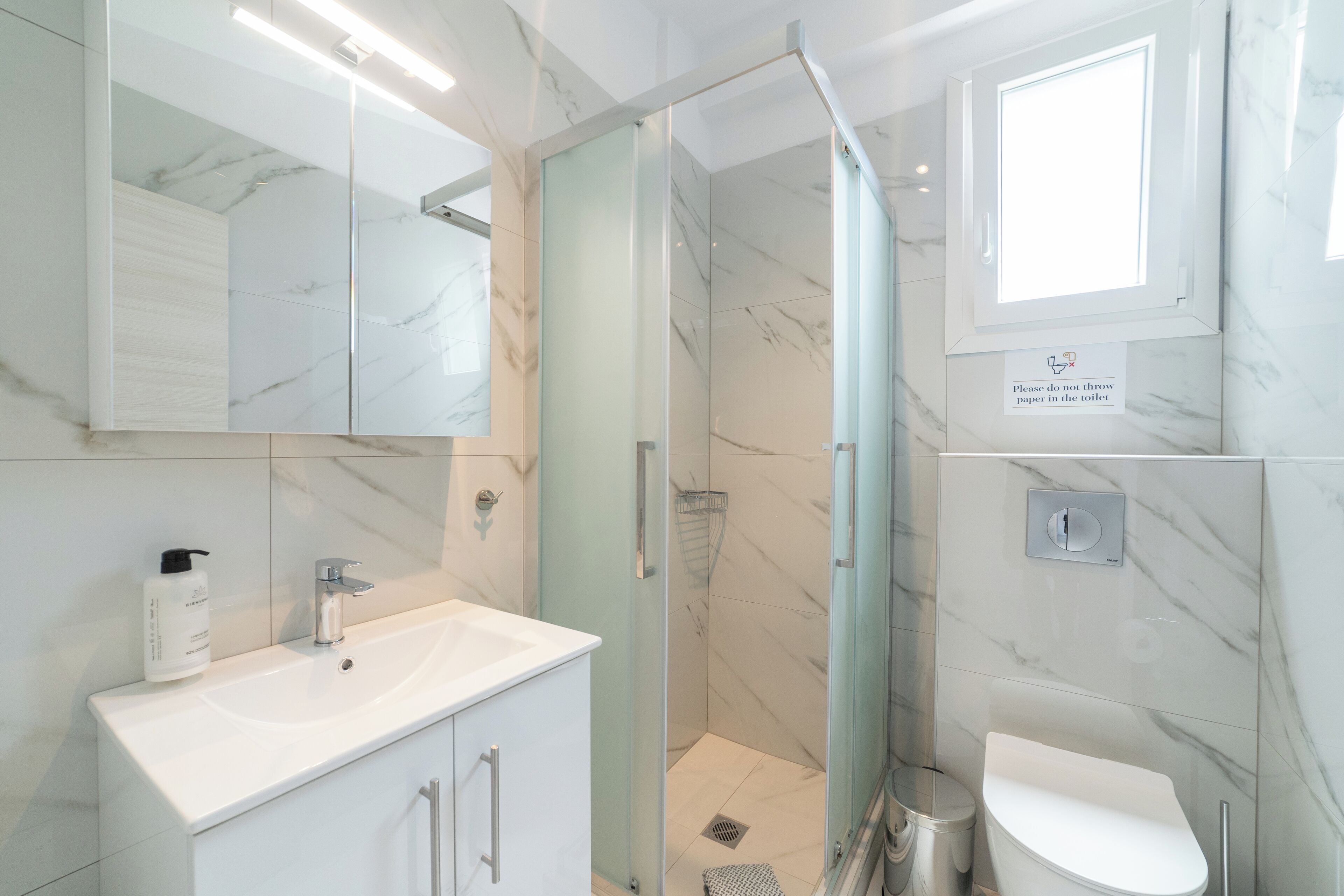 Une salle de bain moderne avec une douche à parois de verre, un lavabo blanc et des toilettes.