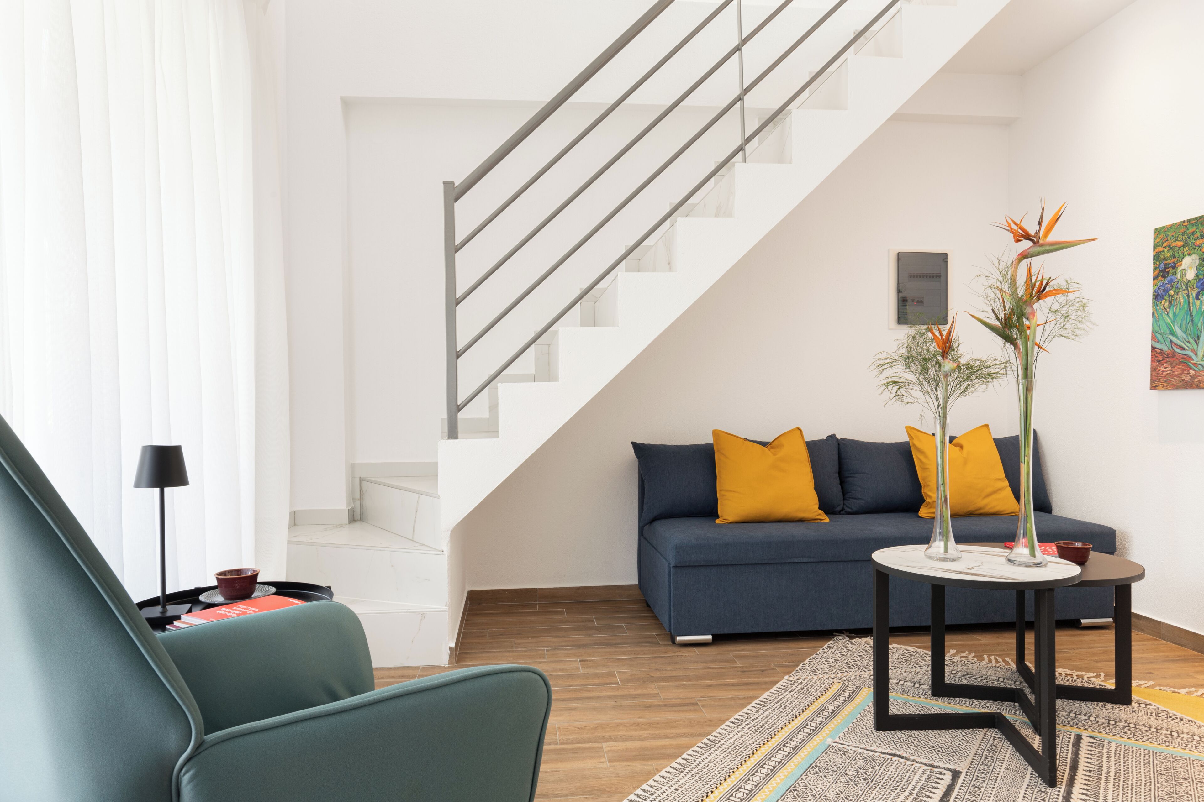 A modern living room with a staircase, a sofa, a coffee table, and a lamp.