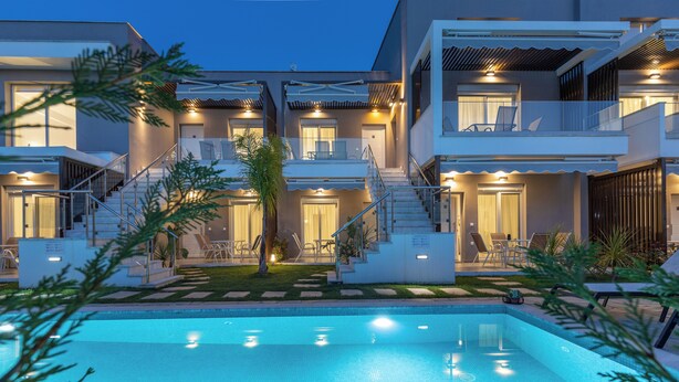 A modern multi-story hotel with a swimming pool, outdoor seating, and a well-lit entrance. - Anastasia Residential Complex (Pangaio)