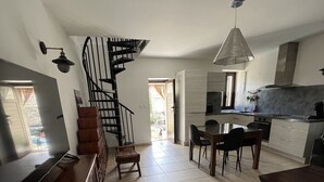 Ein großzügiger Wohnbereich mit Treppe zu einer oberen Etage, einem Essbereich und einer Küche mit modernen Geräten.