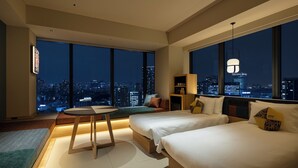 A modern hotel room with two beds, a small table, and a view of the city at night. - OMO5 Tokyo Gotanda by Hoshino Resorts (Tokyo)