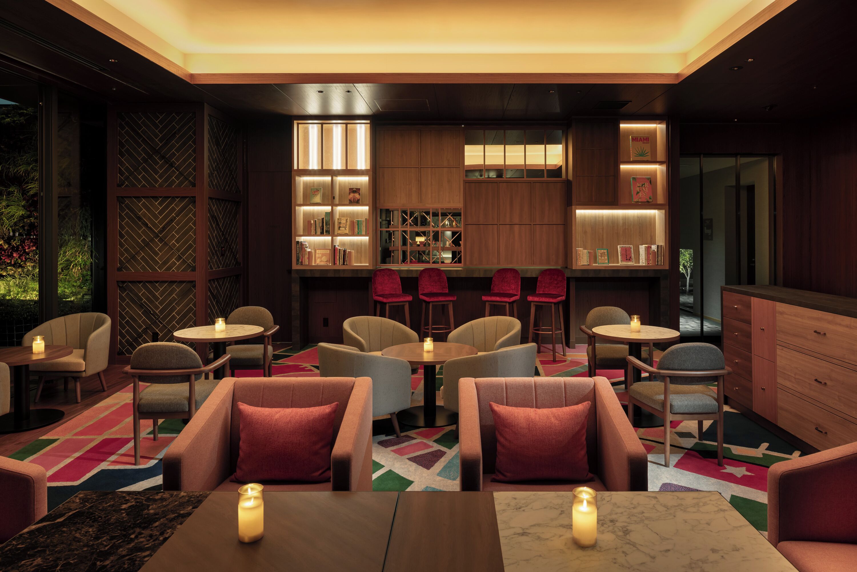 A modern lounge area with seating arrangements, a fireplace, and a bookshelf.