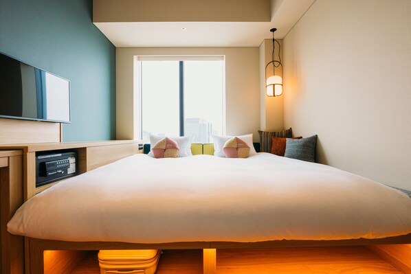Une chambre d’hôtel avec un grand lit, une télévision, une fenêtre donnant sur la ville et une lampe de chevet.