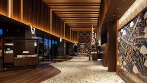 A spacious lobby with wooden paneling, a central seating area, and a large wall mural. - OMO5 Tokyo Gotanda by Hoshino Resorts (Tokyo)