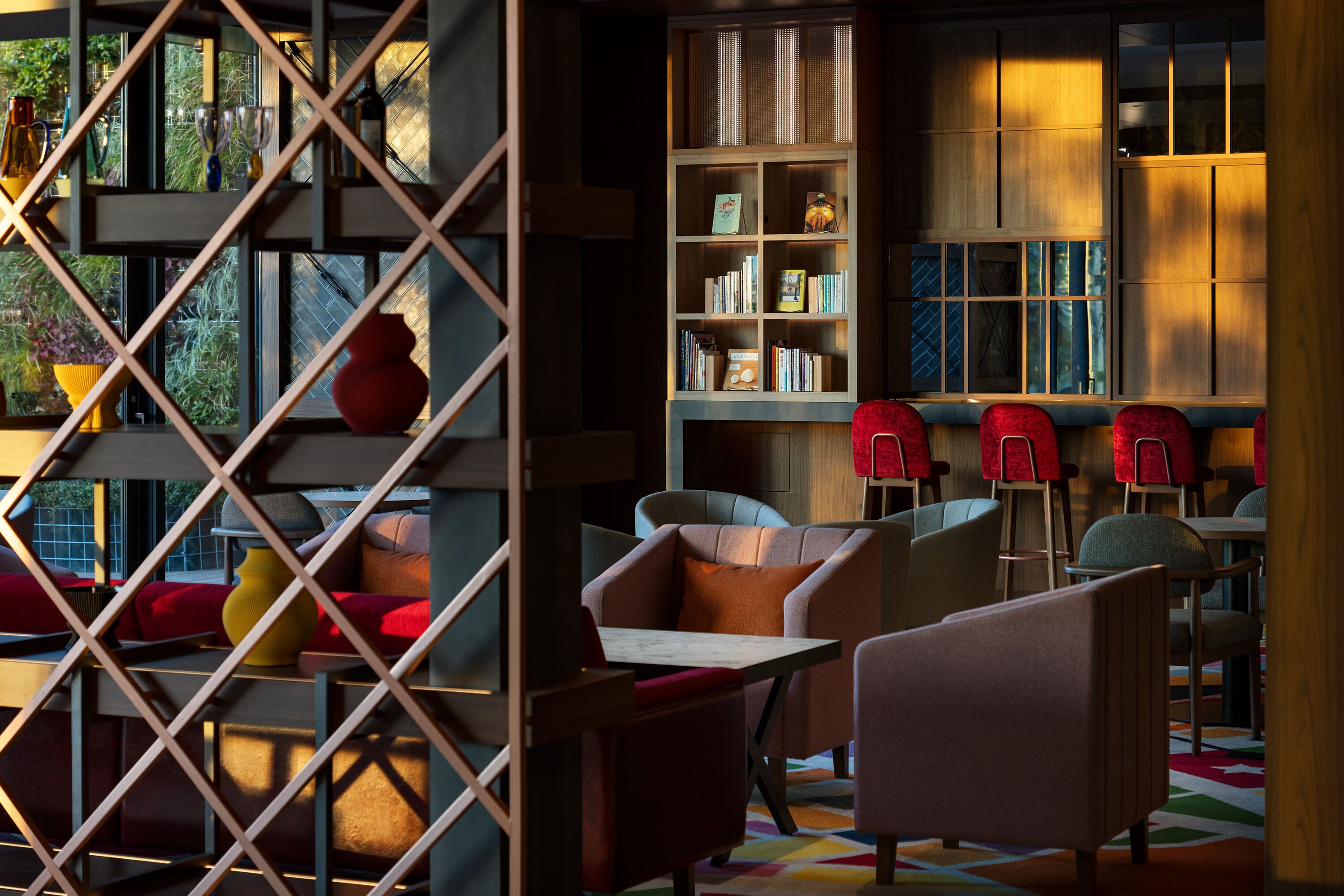 A modern interior with a wooden bookshelf, comfortable seating, and a patterned floor.