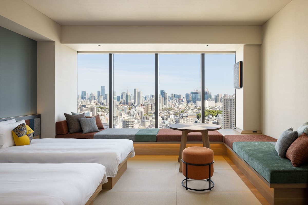 Une chambre d’hôtel moderne avec deux lits, un coin salon et une vue sur la ville.