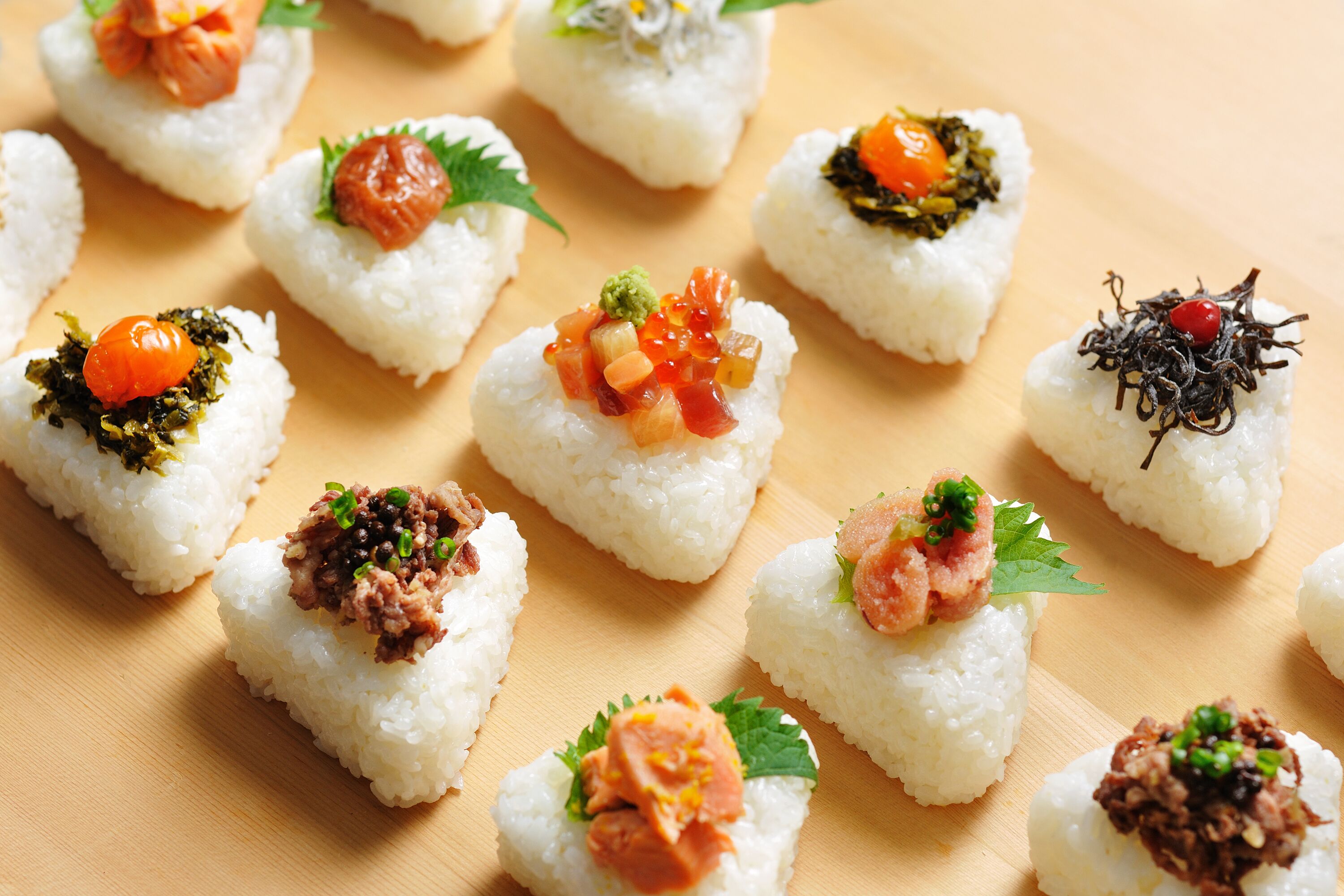 A variety of sushi pieces arranged on a wooden surface.