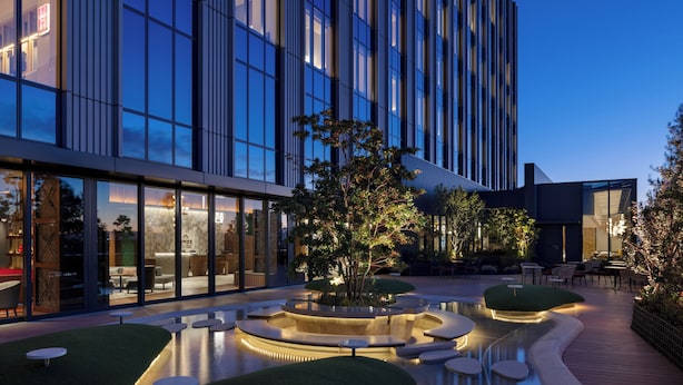 A modern hotel exterior with a courtyard featuring a circular water feature, seating areas, and a well-lit entrance. - OMO5 Tokyo Gotanda by Hoshino Resorts (Tokyo)