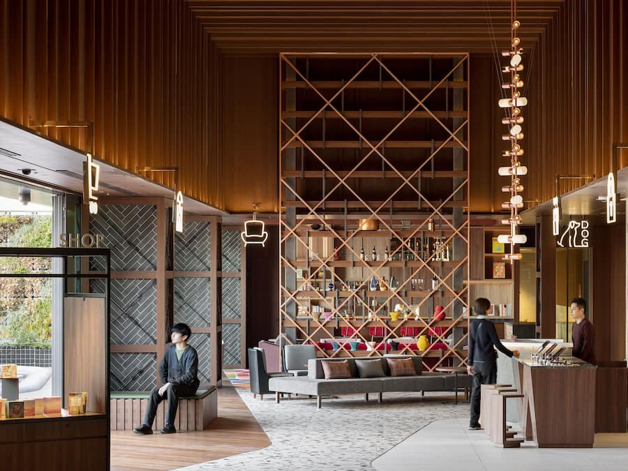 A modern interior with a wooden panel wall, a central seating area, and a reception desk.