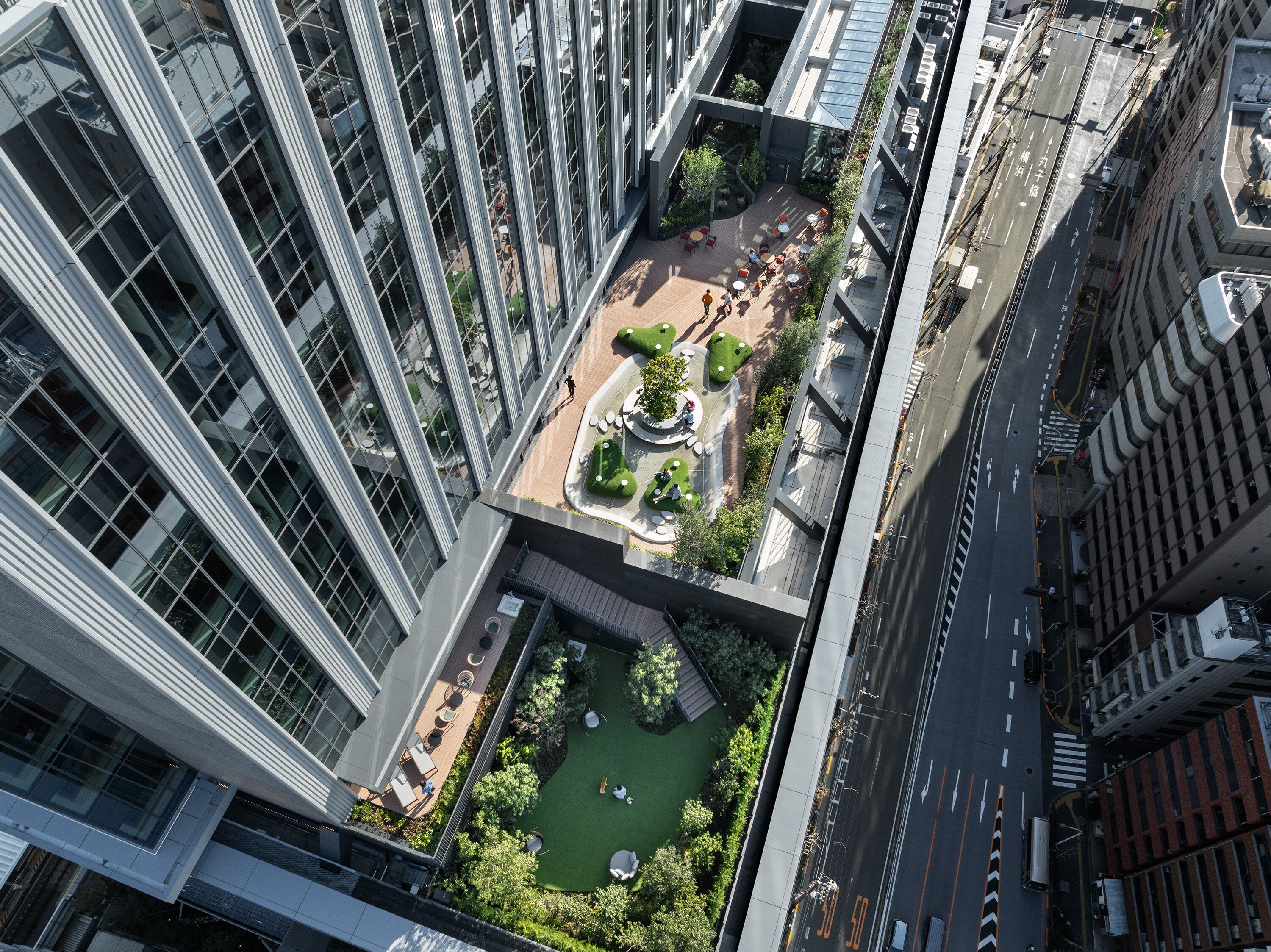Um edifício alto com um jardim no terraço, incluindo áreas de estar e um pequeno lago.