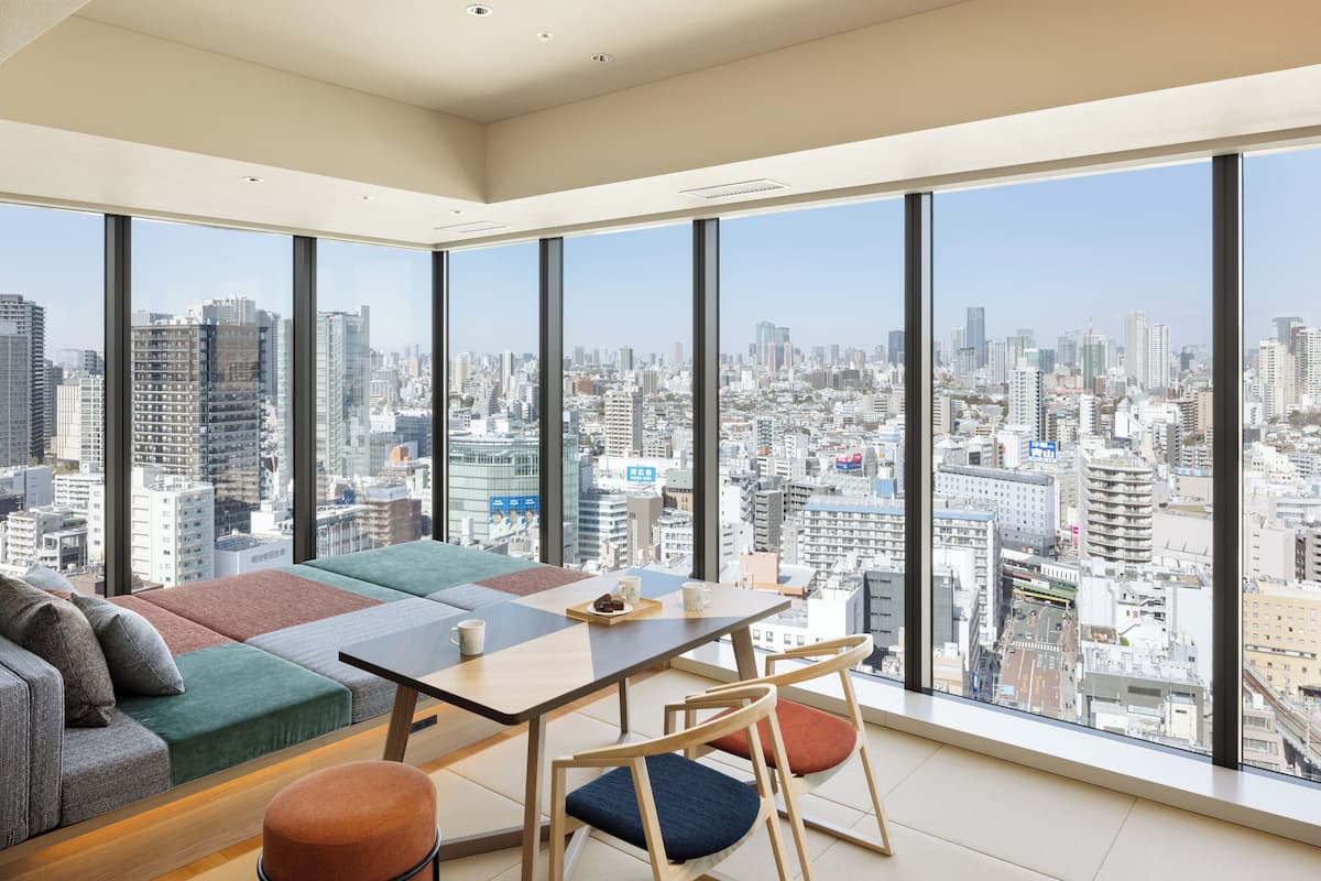 Une chambre d’hôtel située dans un immeuble de grande hauteur, offrant une vue imprenable sur la ville, et comprenant un canapé, une table et des chaises.