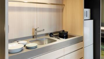 A modern kitchen with a stainless steel sink, a black electric kettle, and a white refrigerator.