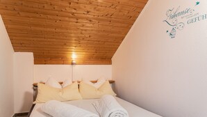A hotel room with a wooden ceiling, a bed with white linens, and yellow pillows.
