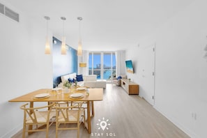 Un salon moderne avec un coin repas, de grandes fenêtres et une vue sur la ville.