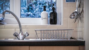 Een keukenkraan met een moderne kraan, een fles afwasmiddel en een handzeepdispenser.