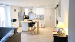 Une cuisine moderne avec des meubles blancs, un îlot central et un coin repas comprenant une table et des chaises.