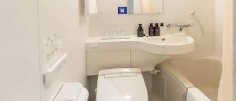 Un baño pequeño y limpio con inodoro, lavamanos y bañera. Hay artículos de aseo en la encimera.
