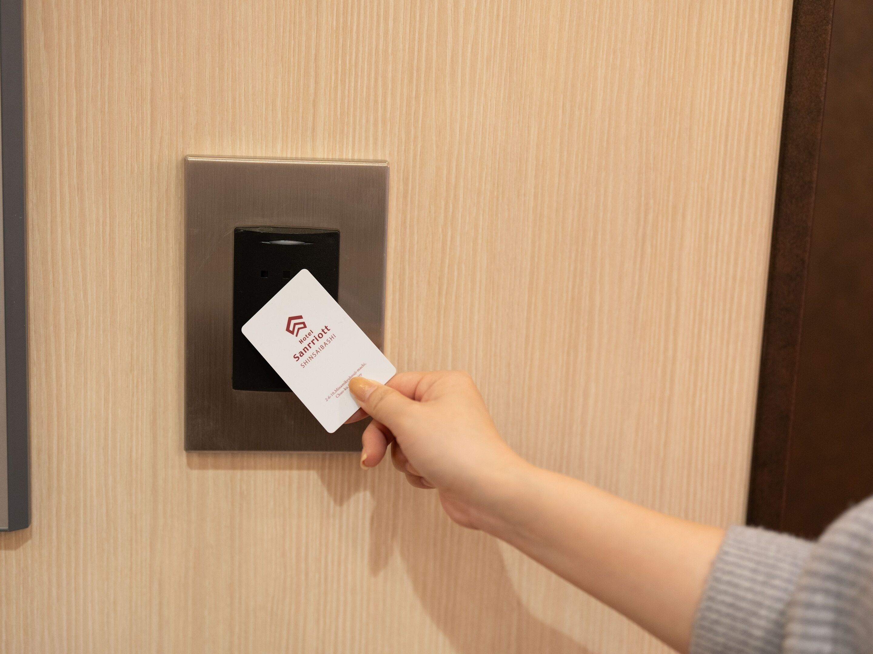 A hand holding a hotel card in front of a card reader.