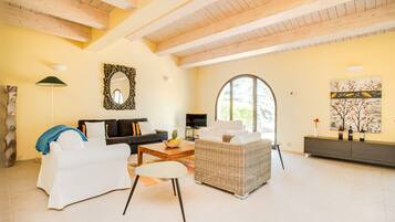 A spacious living room with a high ceiling, a large window, a fireplace, and a modern fireplace mantel.