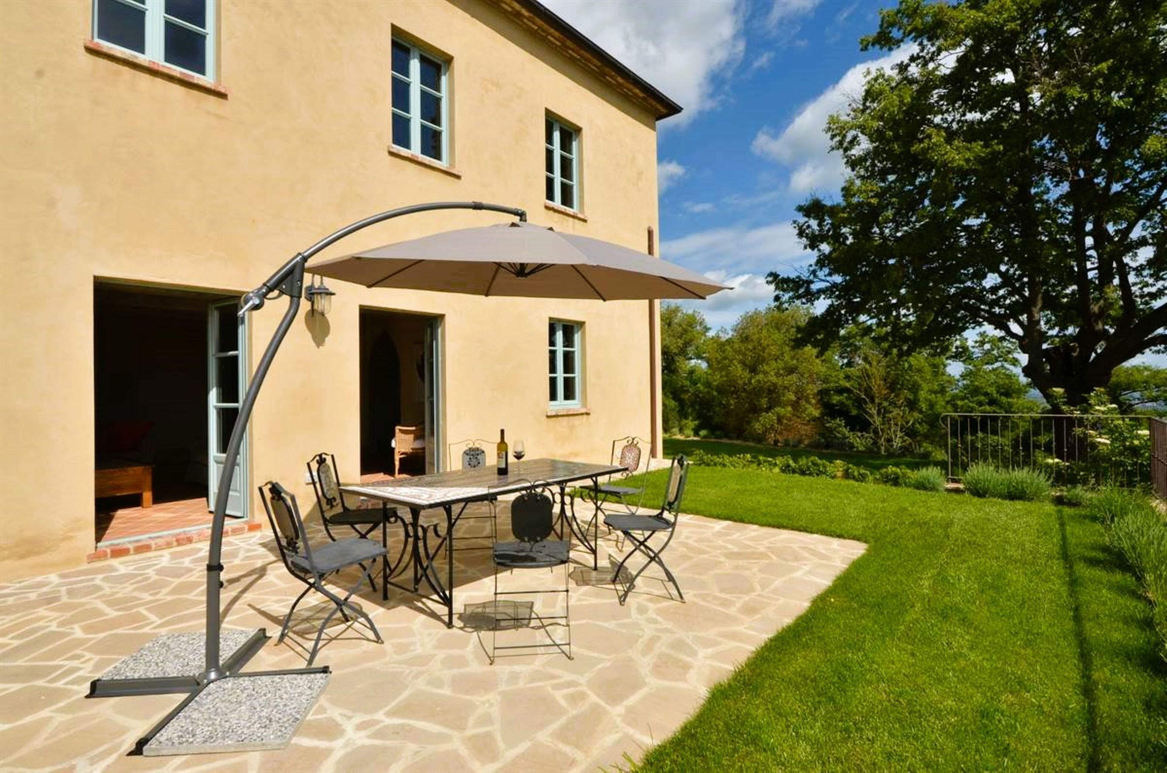 An outdoor patio with a table and chairs, a pergola, and a stone floor.