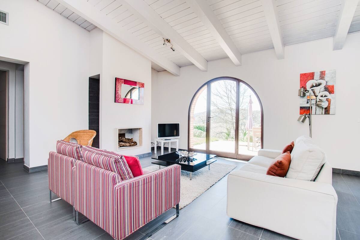 A modern living room with a striped sofa, a white sofa, a black coffee table, and a fireplace.