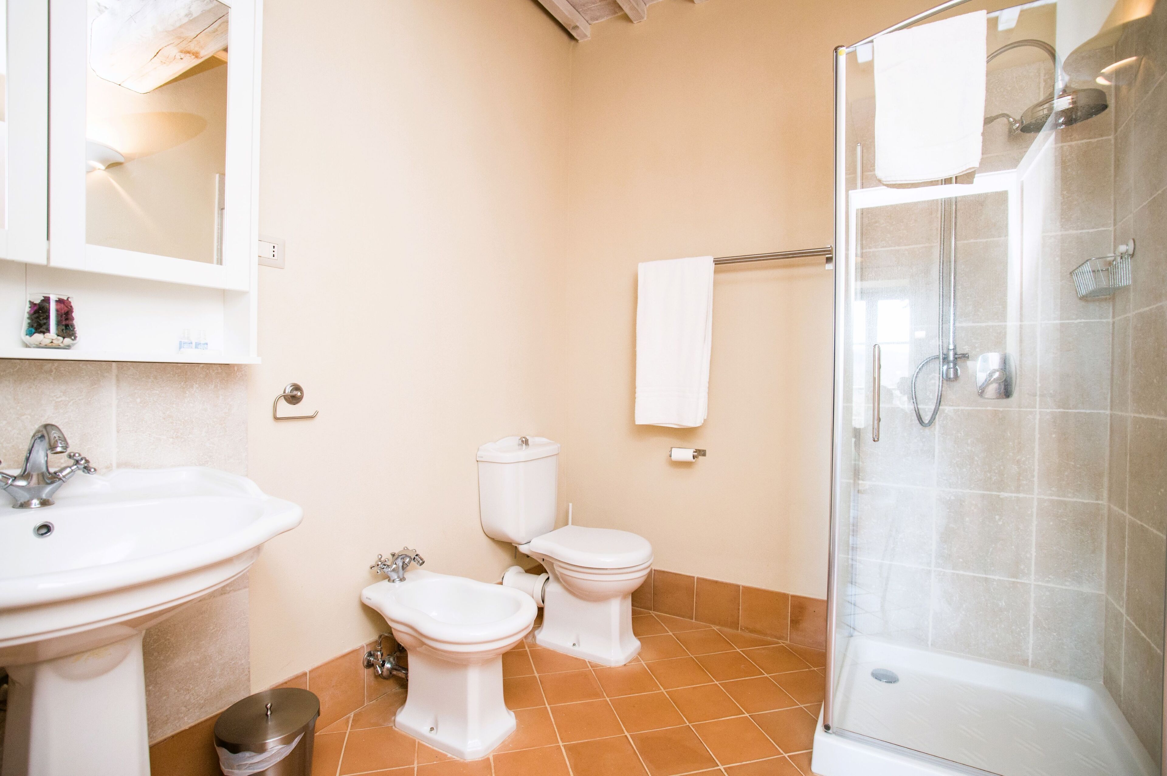 A bathroom with a sink, bidet, toilet, and a glass-enclosed shower.