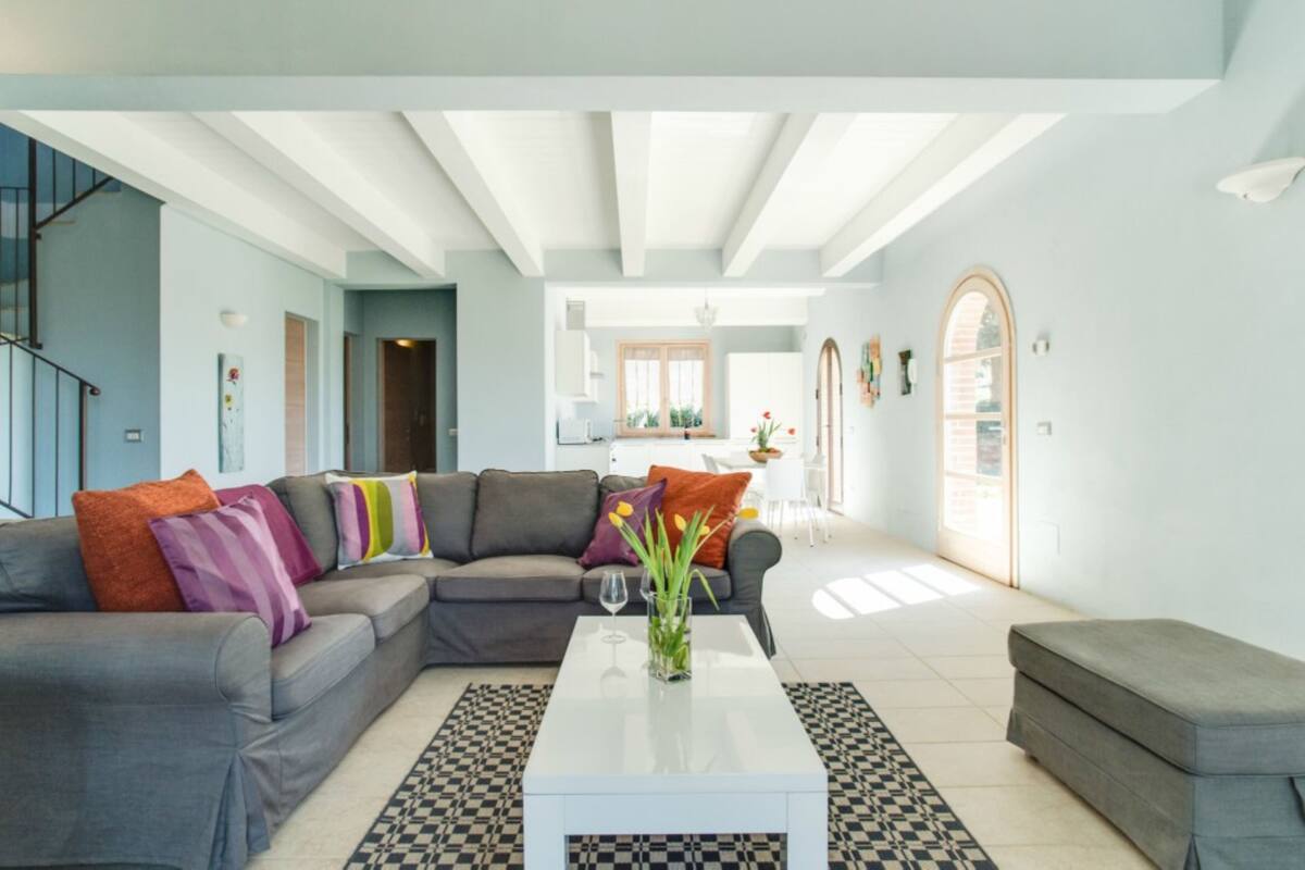 A modern living room with a grey sofa, a white coffee table, and a patterned rug.