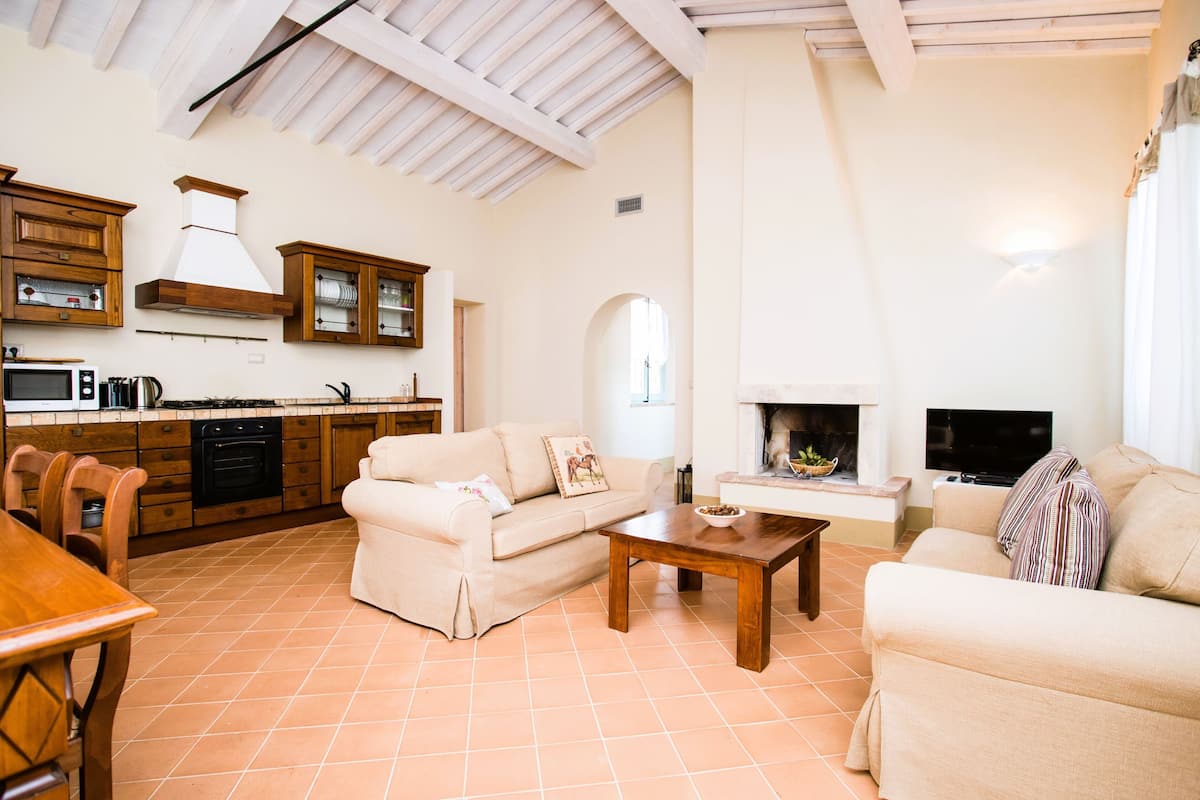 A spacious living area with a fireplace, a kitchen with wooden cabinets, and a dining area with a table and chairs.