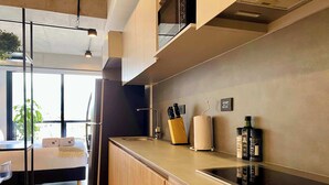 A modern kitchen with a built-in oven, a sink, and a countertop. There is a wooden cabinet and a glass partition. - w* | Marvelous Loft in Polo (Bogotá)
