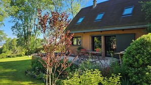 A modern house with a sloped roof, skylights, and a covered patio area with outdoor furniture. - St Georges, Gîte de Campagne, 50 Minutes de Chartres, 1h du Mans 1h50 de Paris (Arcisses)