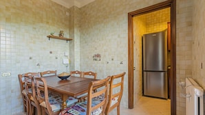 A dining area with a wooden table and chairs, a bowl on the table, and a refrigerator in the background. - Smile House By Apulia Accommodation (Bari)