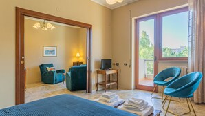 A hotel room with a bed, two chairs, a desk with a computer, a TV, and a large window with a view. - Smile House By Apulia Accommodation (Bari)