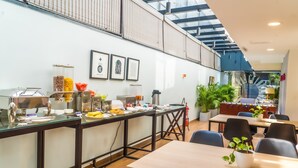 Uma área de refeições moderna com divisória de vidro, um serviço de buffet e vista para o andar superior.