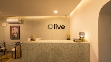A reception desk with a 'live' sign, a framed artwork, a potted plant, and a lamp.