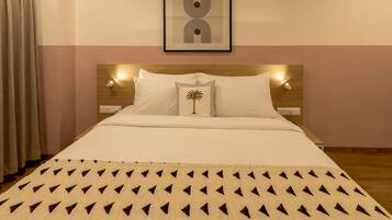 A neatly made bed with a patterned bedspread, a single decorative pillow, and a framed artwork above the headboard.
