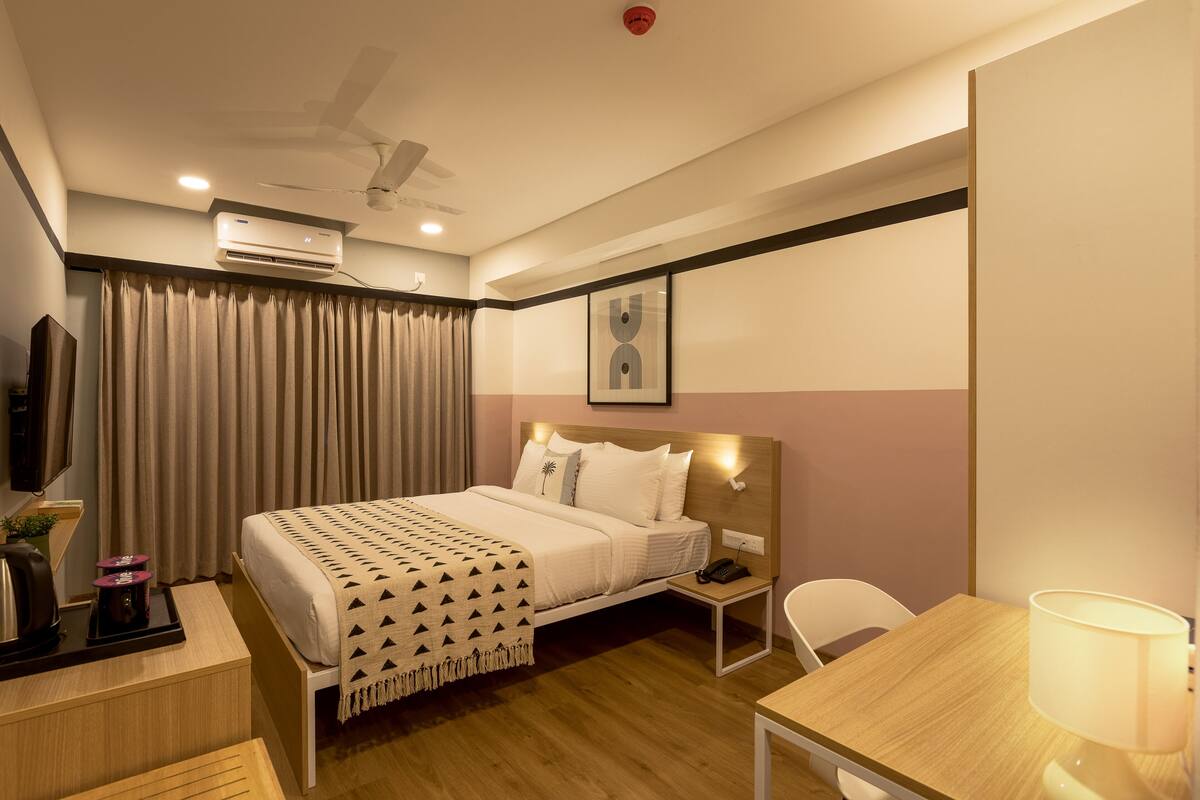 Une chambre d’hôtel comprenant un lit, une table de chevet, une lampe et un bureau avec une chaise.