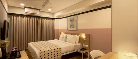 Una habitación de hotel con cama, mesita de noche, lámpara y escritorio con silla.