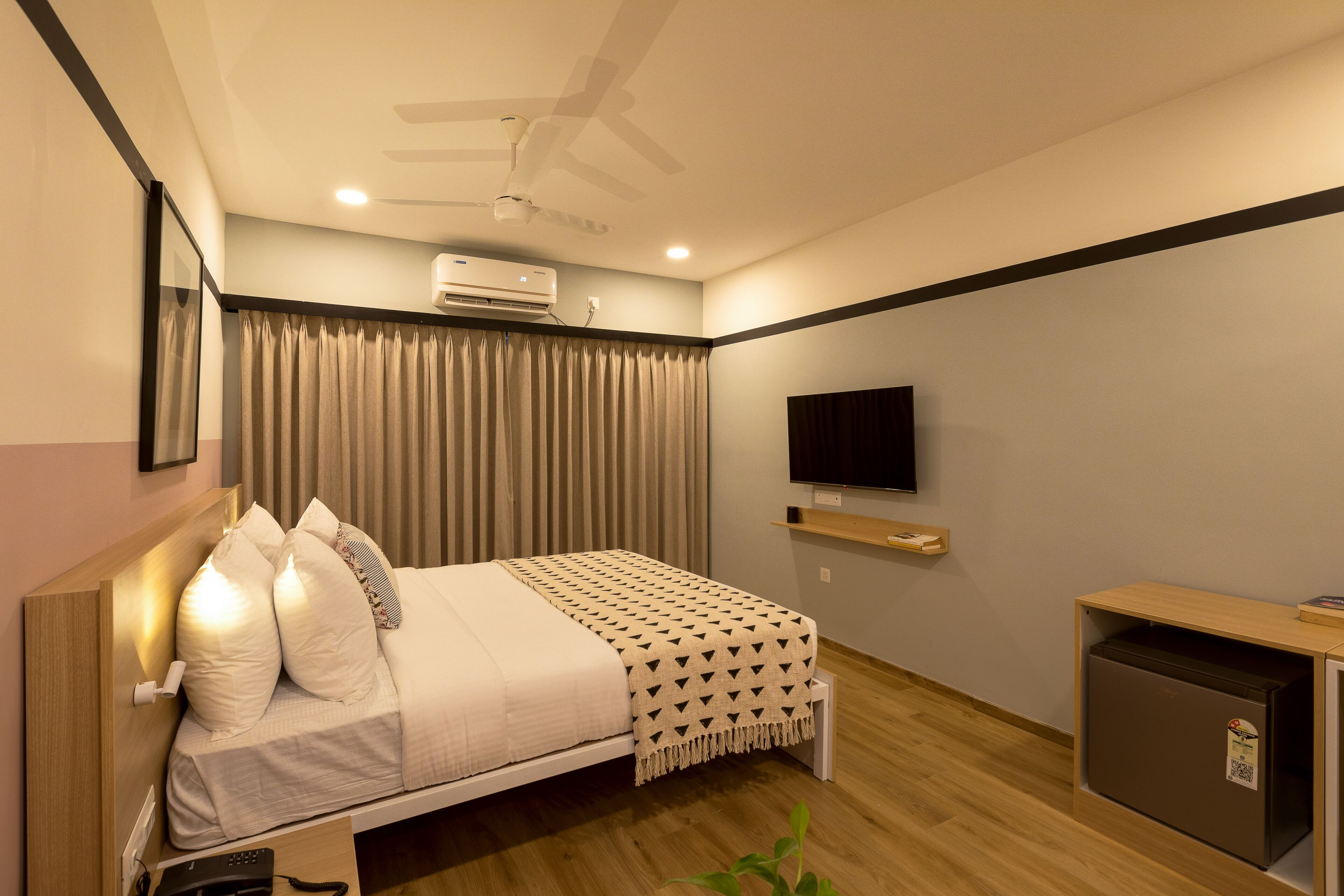 Une chambre d’hôtel moderne équipée d’un lit, d’une télévision, d’un bureau et d’un ventilateur de plafond.