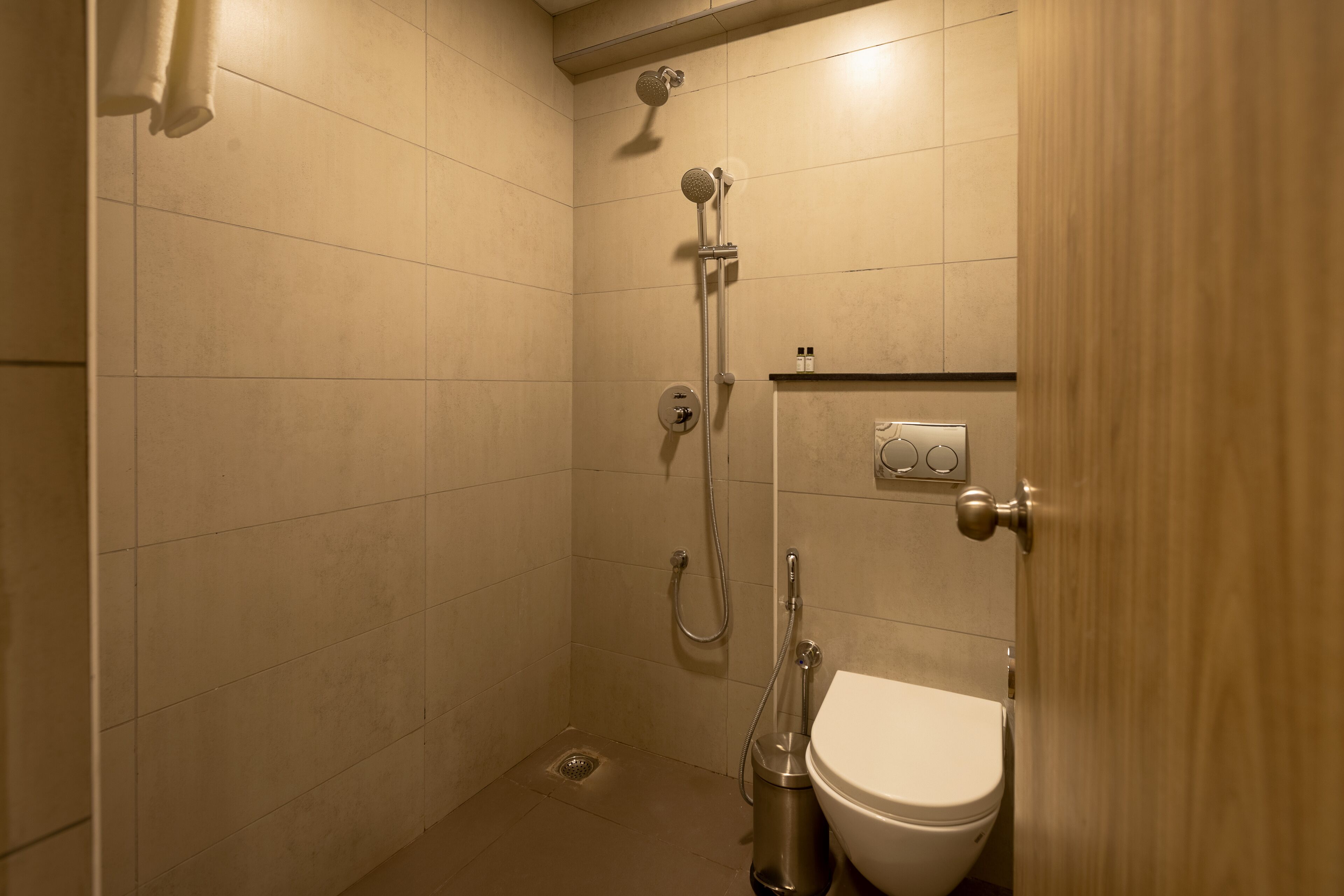 A small, enclosed shower area with a toilet and a towel rack.