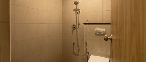 A small, enclosed shower area with a toilet and a towel rack.