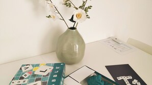 A table with a Scrabble box, a vase with flowers, and a Scrabble game box. - Duplex Hyper Centre-ville (Quimper)