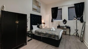 A bedroom with a bed, a wardrobe, a desk, and a mirror. - Dukes Street Apartment Hotel (Liverpool)